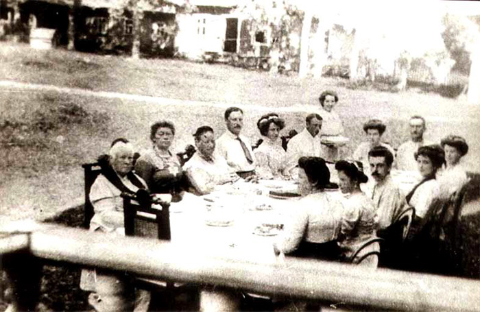 Застолье в Слепневе, лето 1911 года. Фотография, которую уточняет О. Н. Оболенская в письме №2. За столом сидят, слева, по часовой стрелке: В. А. Лампе (урожд. Львова), А. А. Лампе (жена сына В. И. Лампе - Ивана Фридольфовича Лампе), А. И. Гумилёва (урожд. Львова), Д. С. Гумилёв, А. А. Гумилёва (урожд. Фрейганг), В. Д. Кузьмин-Караваев (?), М. А. Кузьмина-Караваева, М. И. Лампе, О. А. Кузьмина-Караваева, А. А. Гумилёва (Анна Ахматова), Н. Л. Сверчков, М. Л. Сверчкова, А. С. Сверчкова (урожд. Гумилёва)